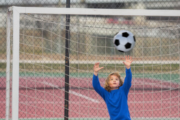 Child boy football or soccer player in action on soccer stadium kicking soccer ball for goal. Concept of sport, competition. Kid kick soccer ball. Kid kicking football ball. Sport for kids.