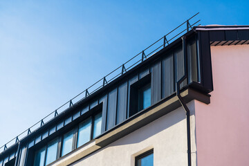 Fototapeta na wymiar Metal facade trim with dark aluminum panels. Modern house facade and roof