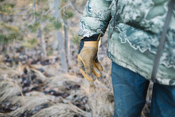 Hunter in camouflage with leather gloves in a forest
