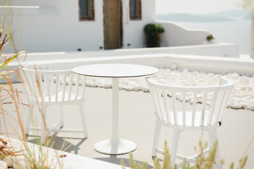 Terrace with white chairs and table design overlooking Oia coastline