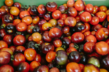 Multi-colored tomatoes of different sizes lie in a box on the counter