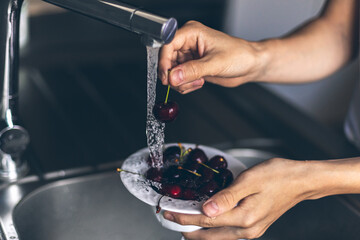 Midsection of human hands washing fresh sweet cherry