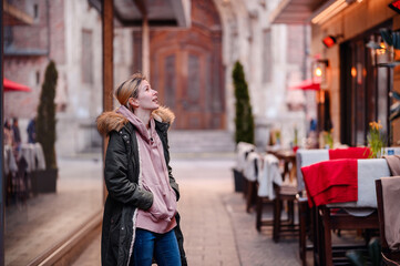 Fototapeta premium Relaxed Walk by City Café, Young woman enjoying a leisurely walk by an outdoor café setting