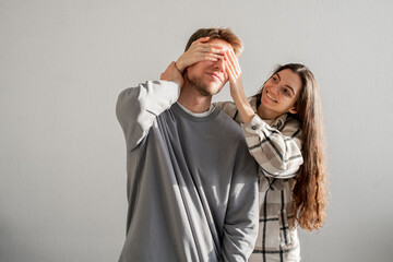 a young lovely couple covering each other's Eyes With Hands in a Playful Surprise Gesture Indoors