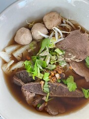 Asian noodle soup with beef meatball with fresh vegetable on wood table vintage style, street food, hot and spicy noodle soup, asian food.