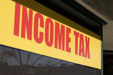 Closeup of the Income Tax sign on the window at the office of a tax preparation service provider.