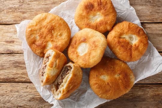 Popular food tatar cuisine peremech belyash pies with mee closeup on the paper on wooden table. Horizontal top view from above