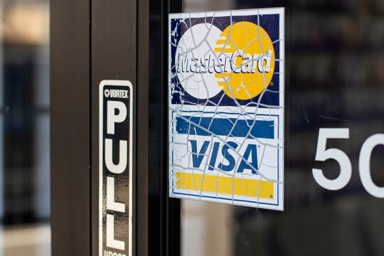Lake Oswego, OR, USA - May 21, 2022: Weathered Mastercard and VISA payment acceptance sticker is seen at the entrance to a local business in Lake Oswego, Oregon.