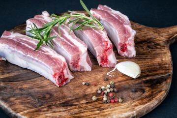 Closeup view of raw ribs with a rosemary and spices on a round wooden cutting board.