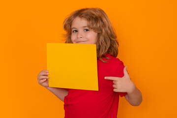 Fototapeta na wymiar Kid showing blank banner on yellow background . Advertising billboard, placard. Lid pointing on empty blank sheet of paper, copy spase. Poster for your text information.