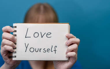 Dziewczyna trzyma kartkę z afirmacja kochaj siebie 