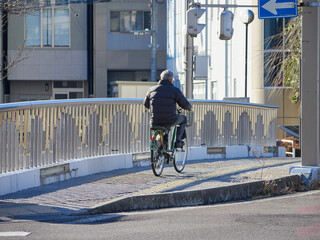 冬の街の橋渡る自転車を乗っているシニア男性の姿