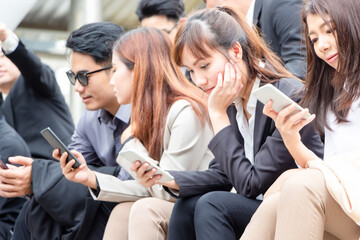 Obraz premium Young businesspeople sitting on stairs with friends, Business people meeting and sharing ideas, Young Asian business team discussing in the morning