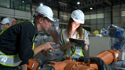 Both of engineers working together in a robotic arm factory, Robotic arm industry and engineering concept.