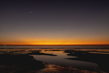 Fototapeta premium A stunning sunset over the Bay of Bengal, with the sky ablaze in rich shades of orange, gold and deep purple as the sun sets behind the horizon.