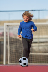 Child boy football or soccer player in action on stadium kicking football ball for goal. Concept of sport, competition. Kid play football ball. Kid with football ball. Sport, soccer hobby for kids.