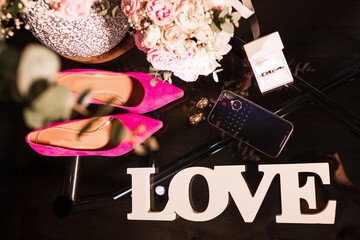 Obraz na płótnie Canvas Wedding accessories on the dark glass table. Rings, shoes, gouquet, phone on open calendar with the wedding date. Weddind concept. Accessories for bride