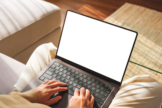 Top view mockup image of a woman working and typing on laptop computer with blank screen on sofa at home