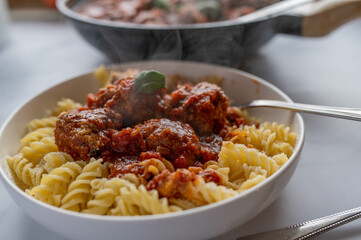 Pasta with meatballs and tomato sauce served hot on a plate.