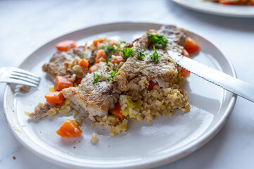 Healthy fish dish with pan fried natural fish fillet with brown rice and vegetables on a plate