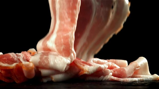 Fresh bacon falling on black background. Filmed on a high-speed camera at 1000 fps. High quality FullHD footage