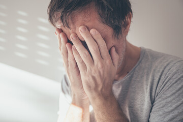 Despair concept, complete loss or absence of hope. Adult caucasian male covering face and crying...