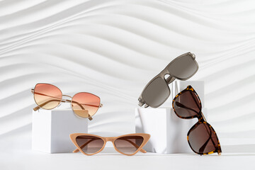 Set of different trendy sunglasses on podiums on white background. Summer fashion eyewear...