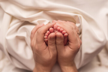 Baby feet of a newborn in dad's hands. On a white background.