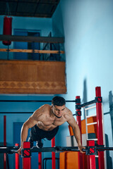Muscular, athletic young man with relief strong body, training shirtless in gym, doing push ups...