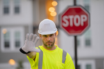 Serious engineer with stop road sign. Builder with stop gesture, no hand, dangerous on building...