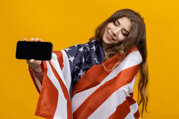 A woman with a flag on her shoulders holds a smartphone. Placing ads on the phone screen. Yellow background