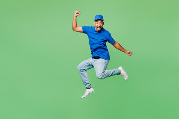 Fototapeta na wymiar Full body surprised shocked fun delivery guy employee man wear blue cap t-shirt uniform workwear work as dealer courier jump high do winner gesture isolated on plain green background. Service concept.