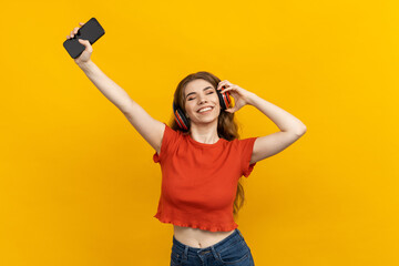 A woman enjoys high-quality sound listening to music in new headphones. Yellow background