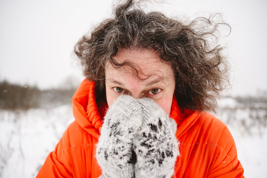 Mature woman covering face with hands in mittens