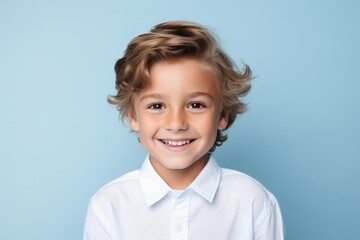 Portrait of a smiling little boy in a white shirt on a blue background