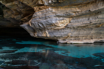 Serene Waters Beneath Ancient Stratified Rock Formations
