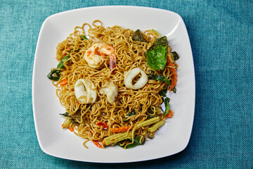 Stir-fried spicy instant noodle with shrimp and squid on plate