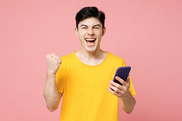 Young Caucasian happy man he wears yellow t-shirt casual clothes hold in hand use mobile cell phone...
