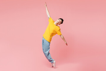 Full body young man wears yellow t-shirt casual clothes stand on toes with outstretched hands lean...