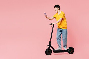 Full body side view young man he wears yellow t-shirt casual clothes driving electric scooter use...