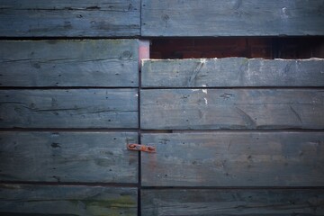 The wooden gates are closed. Broken board in the gate. Wooden background.