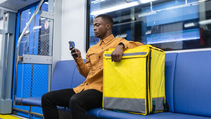 A courier with a mobile phone rides in a subway car during the execution of an order