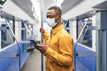 Portrait of a man in a protective mask in a subway car. A man spends time on a mobile phone