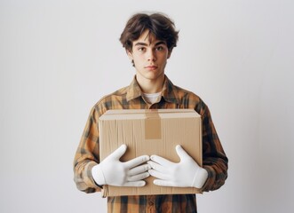 Young male in white gloves holds a large cardboard box against a white background, moving day image