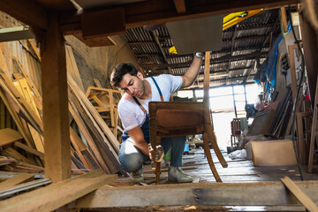Carpenter man doing diy chair in vintage carpentry wood working shop - obrazy, fototapety, plakaty