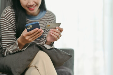 Happy young woman holding credit card and using smartphone for online shopping or check balance