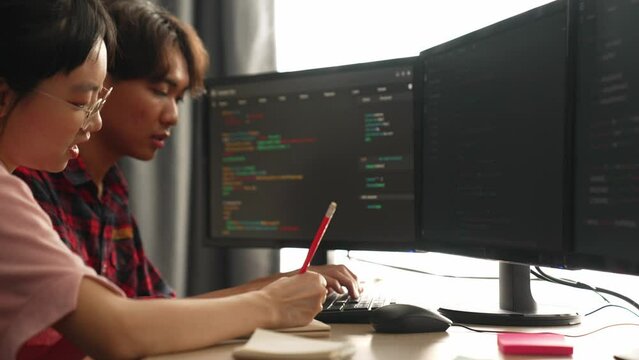 Slow motion back end software developer engineer for computer programming working together on debugging writing computing code, solving complex algorithms display on monitor in office. Burgeoning