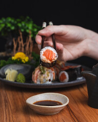 woman dipping salmon maki sushi roll in soy sauce