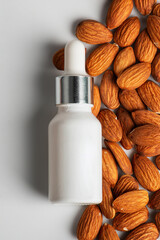 Cosmetic product in tube, bottle, lotion or serum with almonds seed on white background. 