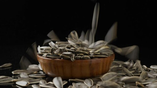 black sunflower seeds falling on table.